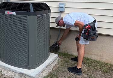 Joel Schupp, licensed home inspector in Round Rock TX, inspection an air-conditioning unit.